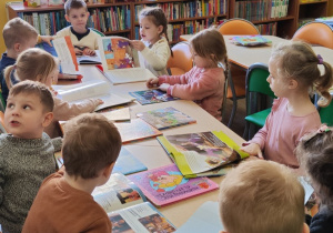 Dzieci oglądają książki o różnych zwierzętach.