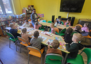 Dzieci oglądają książki o różnych zwierzętach.