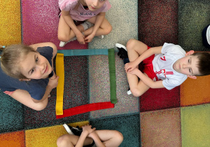 Dzieci układają figury geometryczne z szarf.