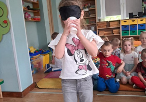 Dziewczynka odgaduje smak soku owocowego.