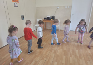 dzieci chodzą po kole utrzymując gumę kolanami