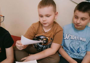 Chłopiec losuję kartkę ze słowem określającym intonację wypowiedzi.