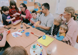 Rodzice i dzieci podczas warsztatów, wykonują skrzyneczkę na zioła.