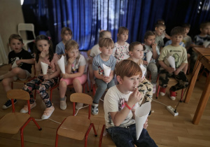 dzieci oglądają bajkę i jedzą popcorn