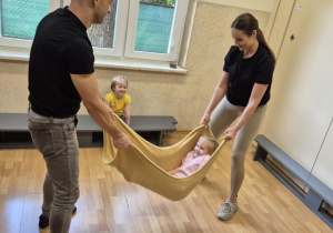 Rodzice bujają dzieci w kocyku