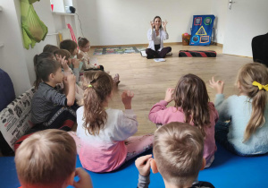 Dzieci wspólnie z Panią psycholog uczą się słów w języku migowym.