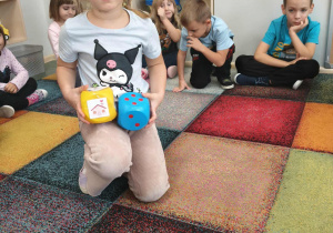 Dzieci uczestniczą w grze przy użyciu dużych kostek do gry.