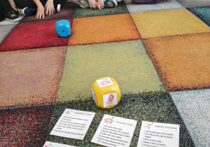 Dzieci uczestniczą w grze przy użyciu dużych kostek do gry.