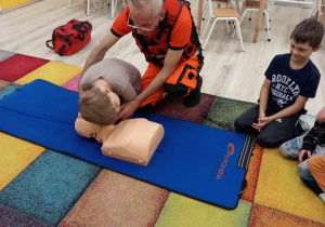 Chłopiec ćwiczy sprawdzanie oddechu na fantomie.