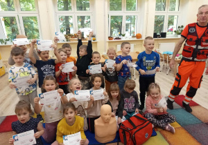 Dzieci pozują do zdjęcia z ratownikiem medycznym.