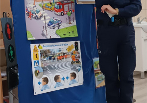 Pani policjantka omawia z dziećmi zasady ruchu drogowego.
