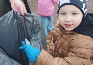 Chłopiec wrzuca śmieci do worka.