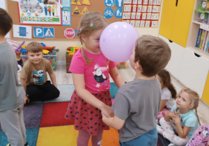 Dzieci tańczą w parach z balonem.