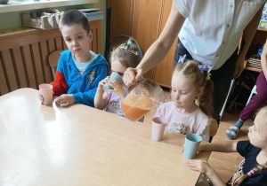 Nauczycielka nalewa dzieciom sok