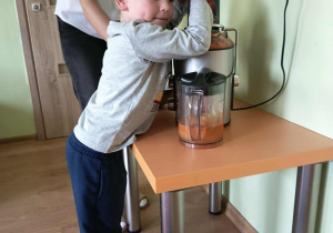 Chłopiec wyciska sok przez sokowirówkę