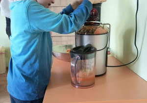 Chłopiec wyciska sok przez sokowirówkę