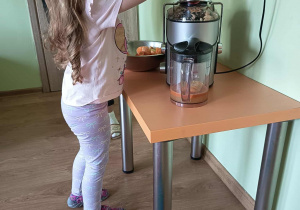 Dziewczynka wyciska sok przez sokowirówkę
