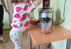 Dziewczynka wyciska sok przez sokowirówkę