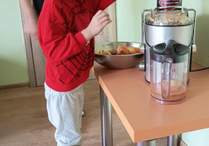 Chłopiec wyciska sok przez sokowirówkę