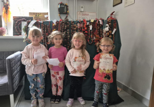 Dzieci pozują do zdjęcia na tle prac konkursowych