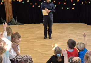 Policjantka stoi na sali przed grupą dzieci