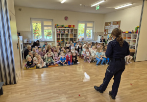 Policjantka stoi na sali przed grupą dzieci