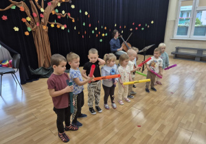 Dzieci stoją trzymając kolorowe rurki