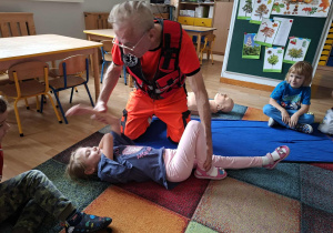 Ratownik medyczny układa dziewczynkę w pozycji bezpiecznej