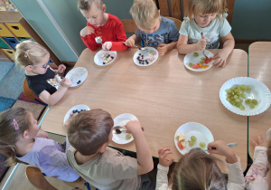 dzieci jedzą sałatkę owocową
