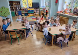 dzieci siedzą przy stołach