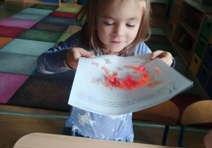 dziewczynka zdmuchuje bibułę z kartki