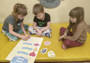 Dzieci przyklejają obrazki i podpisy, tworzą kontrakt grupowy.