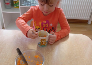 Dziewczynka smakuje mus marchewkowy.