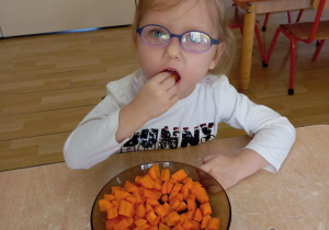 Dziewczynka smakuje surową marchewkę.