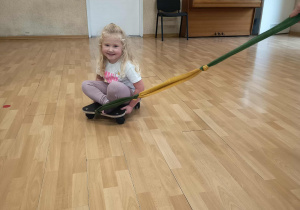 Dziewczynka siedzi na deskorolce terapeutycznej