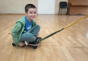 Chłopiec siedzi na deskorolce terapeutycznej