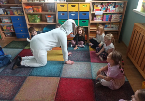 dzieci siedzą w kole, patrzą na przebraną postać psa