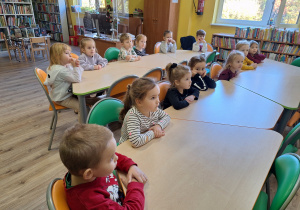 dzieci siedzą przy stołach