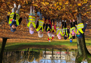Grupa dzieci ustawiła się do zdjęcia w parku na dywanie z liści.