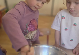 Dziewczynka wsypuje mąkę do miski.