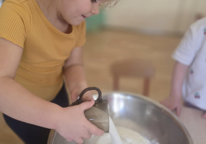Dziewczynka wsypuje sól do miski.