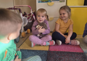 Dziewczynka przytula pluszowego jeża.