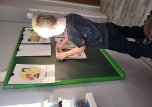 Mikołaj zawiesza obrazek na tablicy.