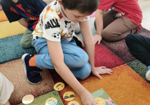 Chłopiec dopasowuje emocję do obrazka.