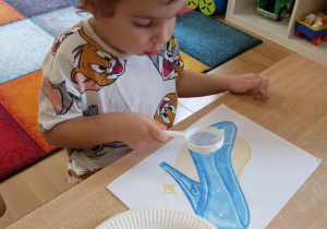 Chłopiec dekoruje pantofelek Kopciuszka.