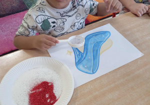 Chłopiec dekoruje pantofelek Kopciuszka.