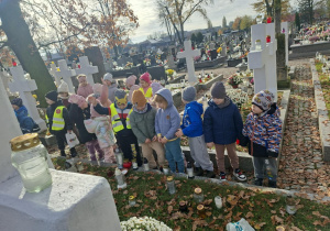 Dzieci wspólnie stoją przy grobach