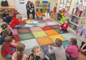 Dzieci siedzą na dywanie.