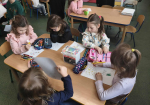 Dzieci koloruja rysunek konturowy.