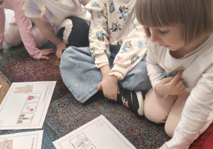 Dziewczynka czyta zdanie zapisane za pomocą piktogramów.